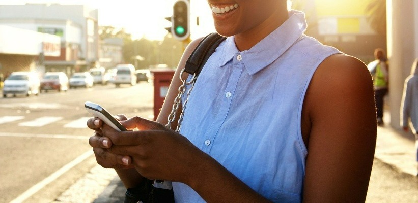 a woman smiling while holding her mobile device