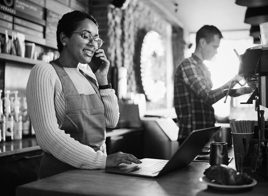 Lady working in a cafe on a laptop computer while on the phone